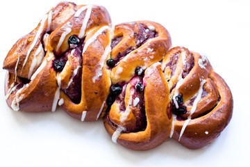 Delicious strudel with blueberries doused with white icing and lies on a white neutral background. Fresh, just pulled from the oven.