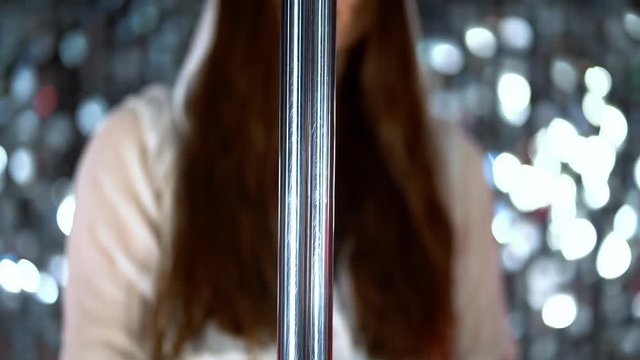 Woman dancing with pylone. Girl puts her hand on pole and starting her sexy dance in night men's club or studio