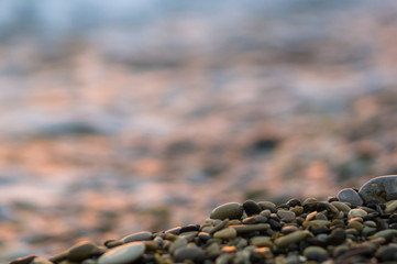 pebble stones on the sea beach, the rolling waves of the sea with foam