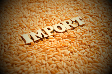 The word IMPORT is composed of wooden letters on the background of wheat grains. Vignetting, toning. Economic relations of the country. Allowing or banning the importation of food from abroad..