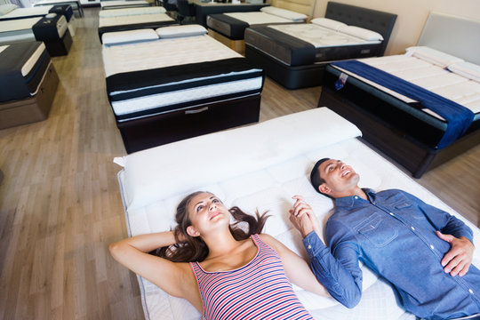 Family couple choosing mattress  in  furniture store