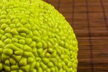 Green fruit of maclura pomifera, osage orange, horse apple, adam apple grow on bamboo mat