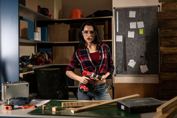 Woman with a drill screwdriver working in the workshop Studio alone