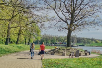 w słoneczny wiosenny dzień para spaceruje po parku wzdłuż rzeki