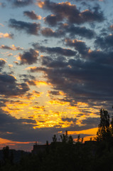 Landscape with dramatic light - beautiful golden sunset with saturated sky and clouds.