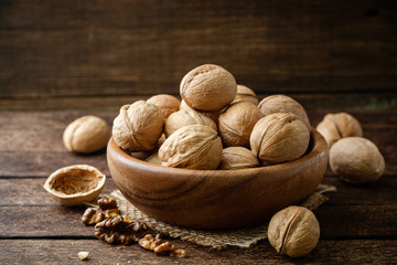 Walnuts in wooden bowl on rustic background. Selective focus.