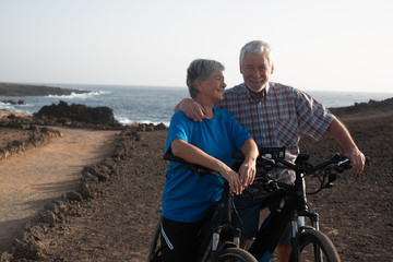Naklejka premium Freedom and happiness for a senior couple of retired persons enjoying bicycling along the footpath, ocean on the background