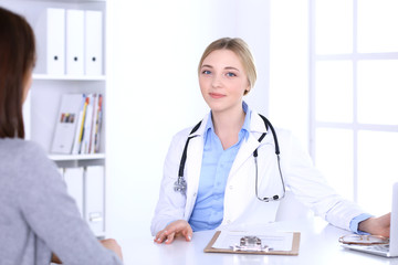 Young woman doctor and patient at medical examination at hospital office. Blue color blouse of therapist looks good. Medicine and healthcare concept