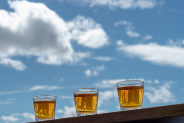 Alcohol shots lined up under blue sky.