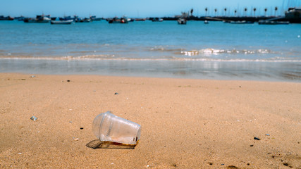Fototapeta na wymiar Rubbish Plastic cup left on the beach make pollution