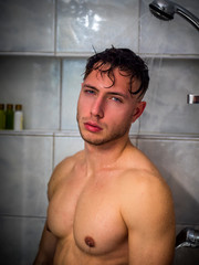 Naked Athletic Young Man Taking Shower in the Bathroom to Refresh, Looking at Camera