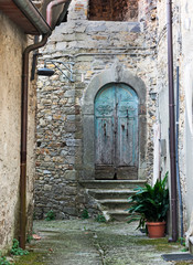Fototapeta na wymiar Ancient carved door and stone doorway with carving, in a small village in Lunigiana, north Tuscany, Italy.