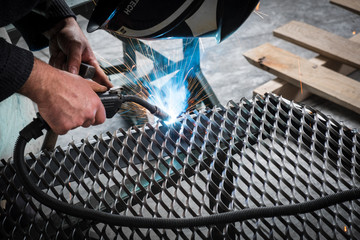 Worker welding steel mesh to the frame with MIG technology - obrazy, fototapety, plakaty