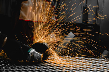Worker cutting the steel mesh with the grinder in the workshop