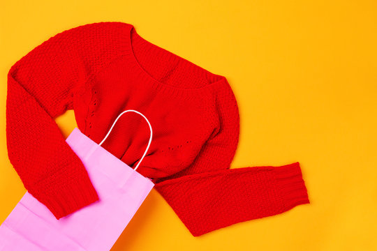 Top view of pink shopping bag with red swether