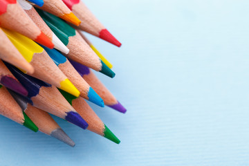 A group of bright wooden pencils lying on a blue background