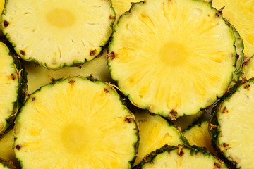Pineapple juicy yellow slices background. Top view.