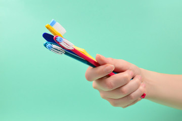 The woman holds toothbrushes in her hand on a green background.