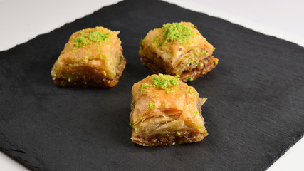 Pistachio baklava on a black plate. Dessert.