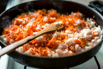 Cooking for soup, chopped carrots and onions are fried in a pan