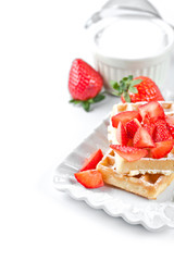 Belgium waffers with sugar powder and strawberries on ceramic plate on white table