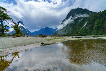 Naklejka na ściany i meble reflections of mountains in the water, milford sound, new zealand 9