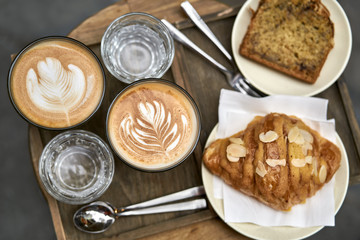 Milk coffee with croissant and bread and water on wooden table