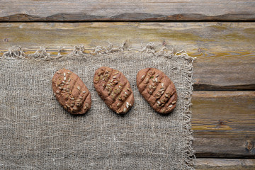 whole wheat bread with sunflower seeds and knife with cutting board and burlap on wooden background, top view 