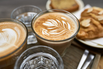 Milk coffee with croissant and bread and water on wooden table