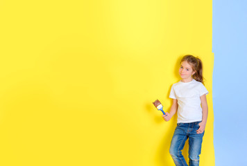 Renovation concept. little girl with a brush for painting stit near the painted wall. Repair in the apartment.