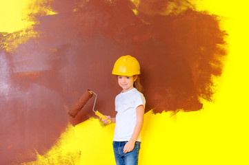 little girl in a construction helmet helps to paint the walls, Repair in the apartment.