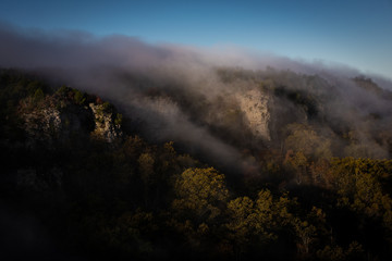 A blanked of fog and mist cover the fall colored trees of the Mount Magazine Arkansas forest at sunrise. The soft, silent mood illustrates the changing season / coming winter in Arkansas state park