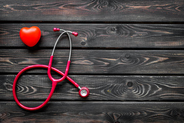 diagnostic and cure of cardiac disease with stethoscope and heart on wooden background top view...