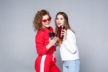 Two strong  woman in red  tracksuit  and jeans , with  with thermos cup in hands !