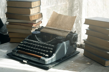 Typewriter and stack of books on a writer table background.