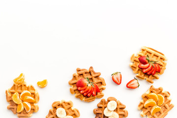 Homemade Viennese waffles with strawberry, tangerine and banana topings on white background top view make up