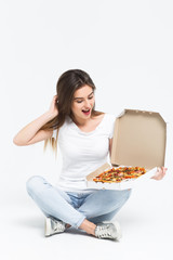 Beautiful blonde hungry woman in white casual shirt sitting on floor and eating pieces of hot tasty pizza. Healthy and junk food concept. Diet. Calories