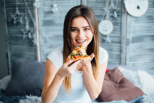 Attractive, and happy smiling girl with slace of tasty pizza and looking to the camera!