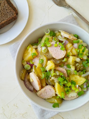 Salad of pickled cucumbers with onions in a bowl, on a light background top view. Next to a fork and rye bread.