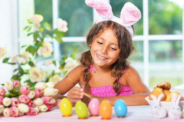 Portrait of little girl painting eggs for Easter holiday