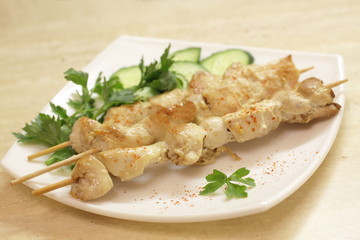 Baked chicken fillet on wooden skewers with cucumber and dill. Barbecue from pieces of chicken on wooden skewers.