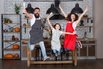 Family having fun cooking together. Teach kid cooking food. Weekend breakfast. Cooking with child might be fun. Having fun in kitchen. Family mom dad and little daughter wear aprons jump in kitchen