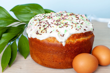 Easter cake and colored eggs on blue background. Holiday food and easter concept. Selective focus. Copyspase