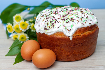 Obraz na płótnie Canvas Easter cake and colored eggs yellow flower blossoms on background. Holiday food and easter concept. Selective focus. Copyspase