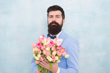 Flowers for her. Man bearded suit bow tie hold tulips bouquet. Gentleman making romantic surprise for her. Flowers delivery. Gentleman romantic date. Birthday greetings. Best flowers for girlfriend