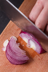 young woman in a gray aprons cuts red onion