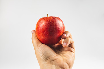 hand holding a red apple fruit against white background