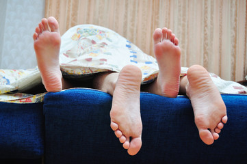 Boy and girl's legs under the blanket
