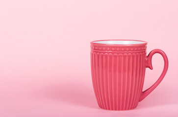 Pink mug. Pink background. Copy space. Pink cup on pink background