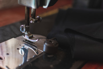 Close up photo of sewing machine with black fabric on the table.